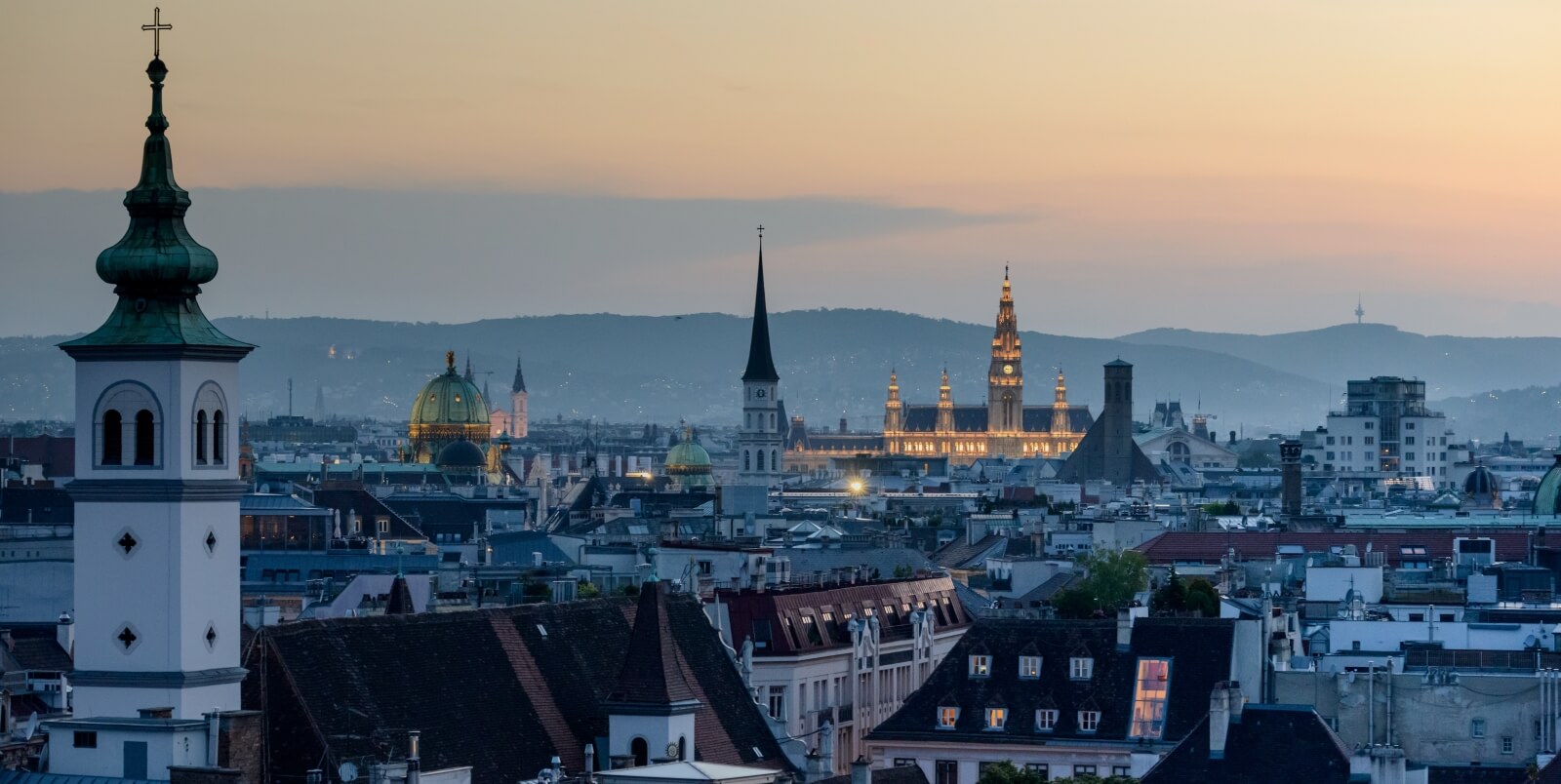 Blick über die Dächer von Wien in Richtung Rathaus bei Dämmerung