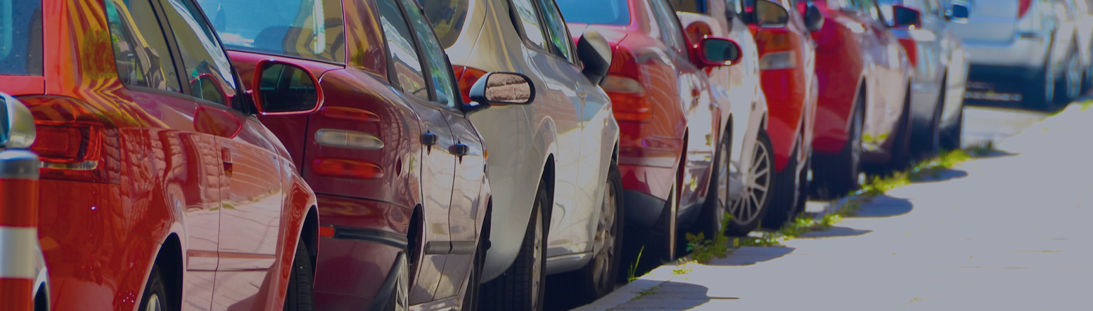 Es sind parkende Autos in unterschiedlichen Farben am Straßenrand zu sehen.