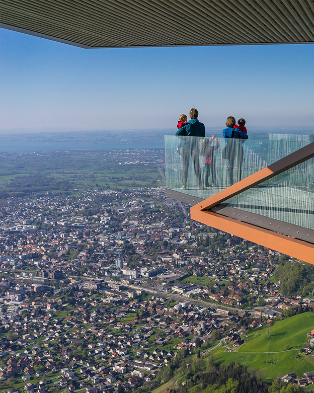 Dornbirner Karren Es ist eine Familie mit drei Kindern zu sehen. Sie steht auf einer Aussichtsplattform mit Blick über Dornbirn. Mutter und Vater halten jeweils ein Kind in der Armen.