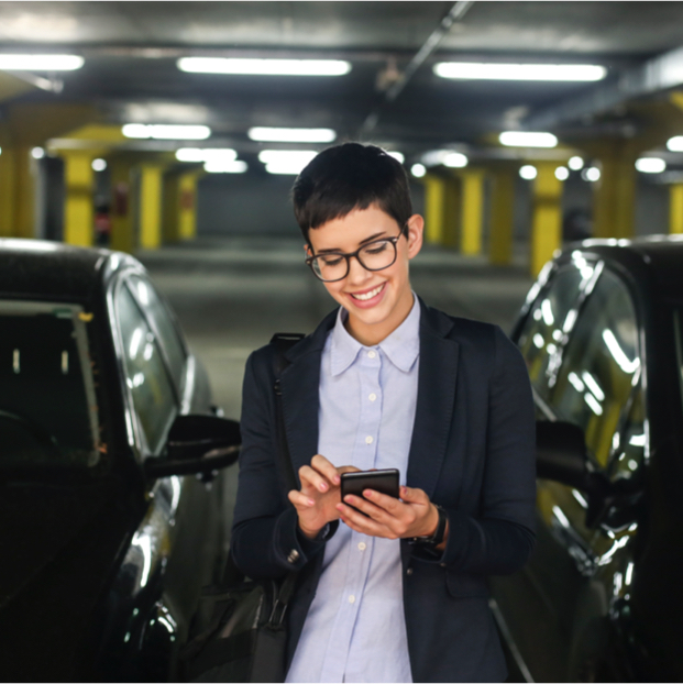 Frau mit Brille und Mobiltelefon in der Hand in einer Tiefgarage
