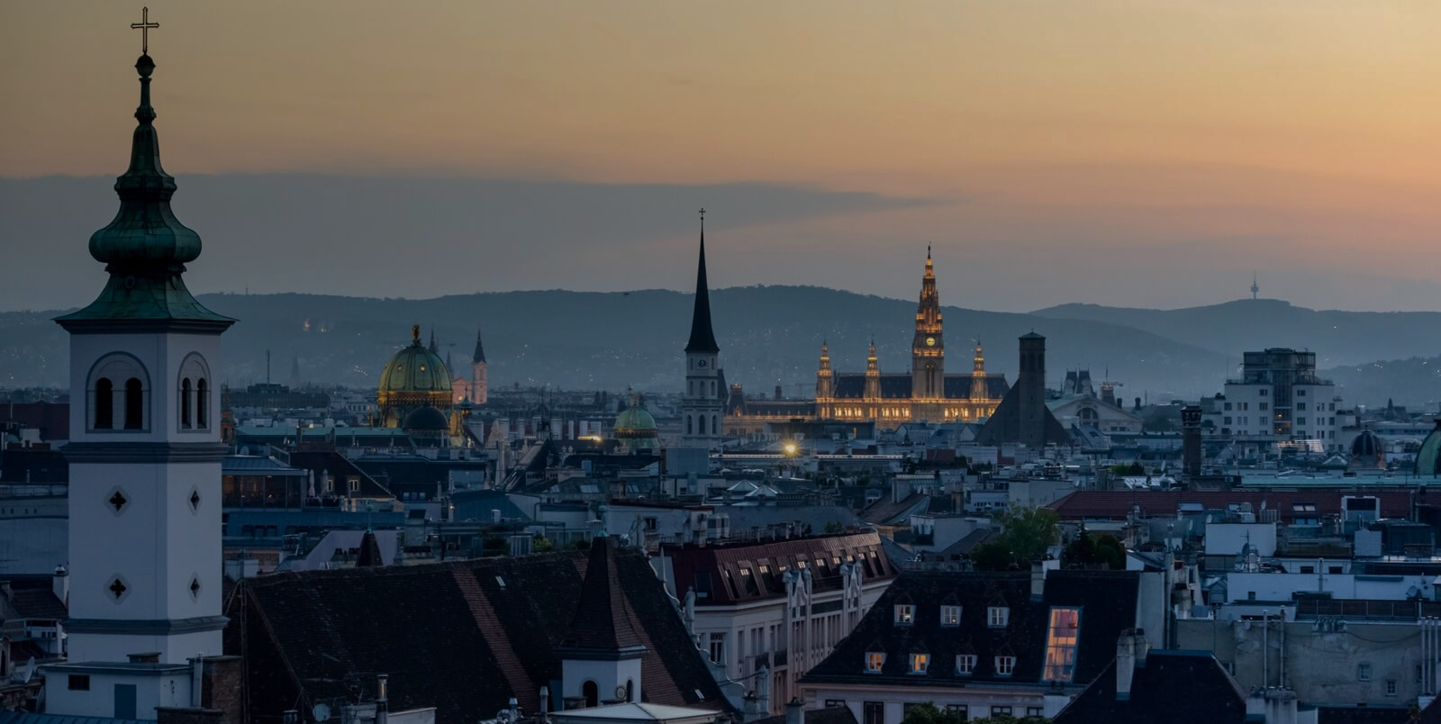 Blick über die Dächer von Wien in Richtung Rathaus bei Dämmerung
